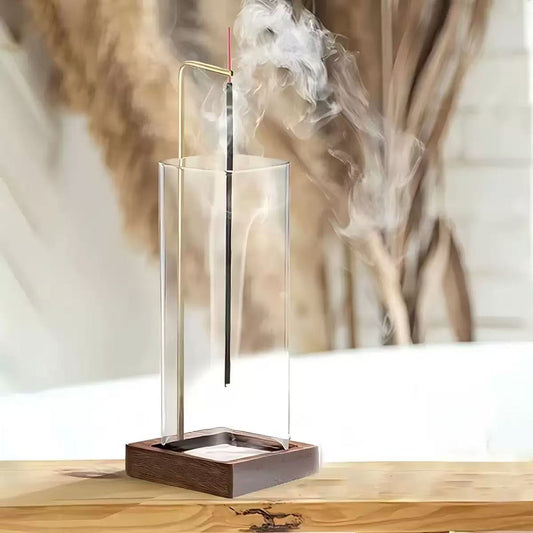 Modern vertical stick incense holder with clear glass cylinder and wooden base, smoke rising elegantly from incense stick