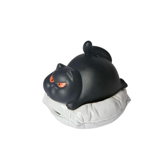 Black ceramic cat incense burner with a playful cat-shaped lid and vivid orange eyes, resting on a soft round cushion against a clean white background.