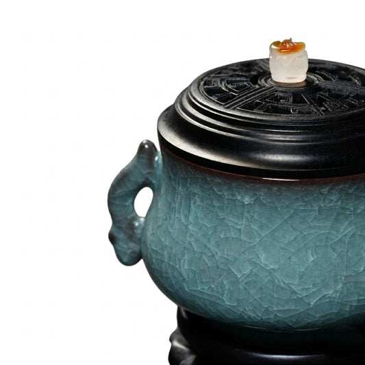 Close-up of a luxury electric incense burner with a Ge kiln ice-crackle ceramic body, black lid, and decorative side handle