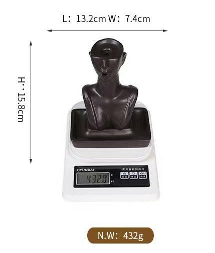Abstract face backflow incense burner in matte black shown on scale with dimensions labeled 15.8cm height, 13.2cm length, 7.4cm width, and weight 432g