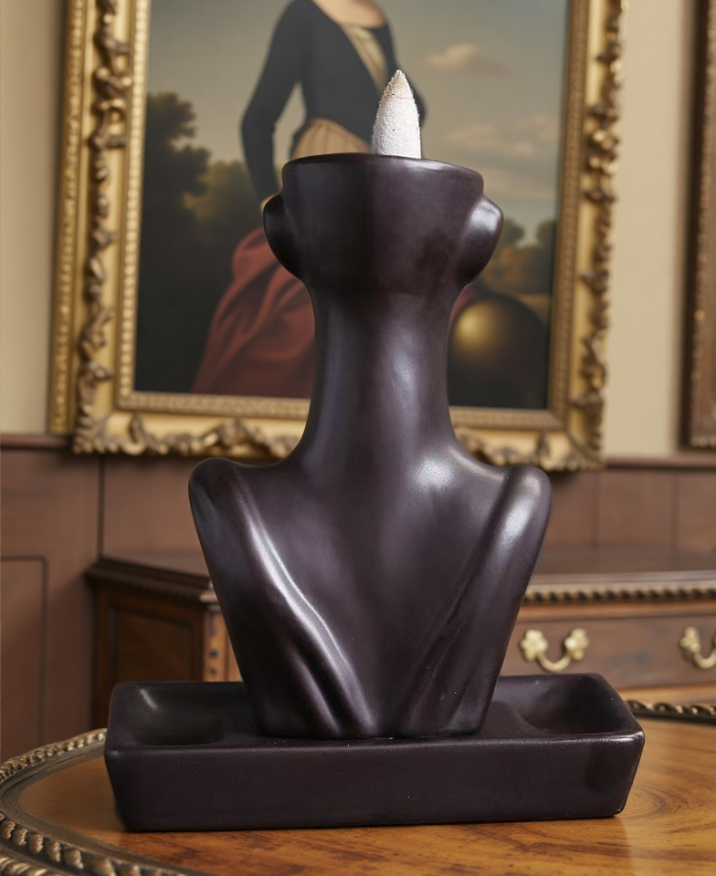 Rear view of matte black abstract face backflow incense burner with cone on top and rectangular ceramic base