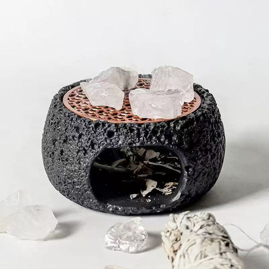 Black handmade cement crystal purifier stove with rosewood grate and raw crystals on top, styled with white sage bundle and clear quartz pieces on a neutral background