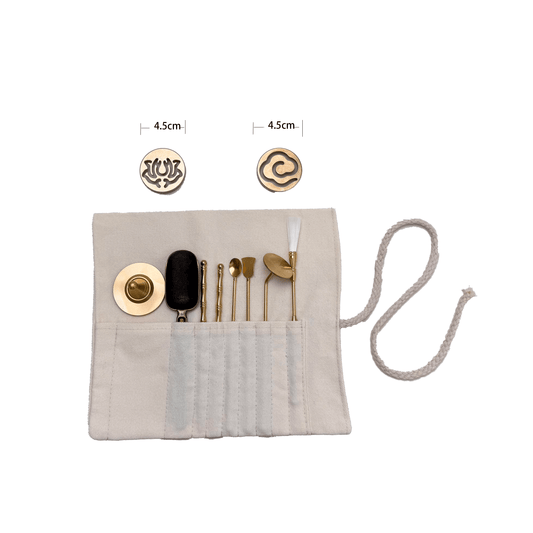 Top view of 8-piece brass incense stamp tool kit with two 4.5 cm pattern molds and various incense tools, arranged in cloth wrap on white background