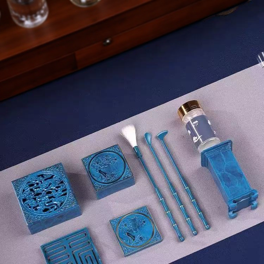 Overhead view of blue-glazed ceramic incense tools including molds, burners, and powder bottle arranged on cloth