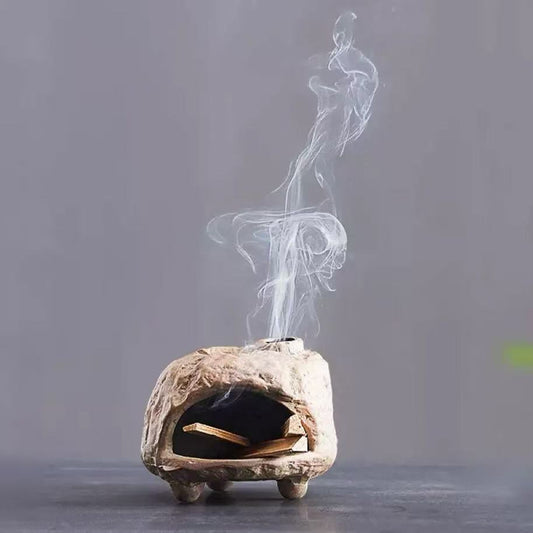 Handmade ceramic incense burner with gentle diffusion groove, releasing spiral smoke from palo santo wood in a minimalist dark background