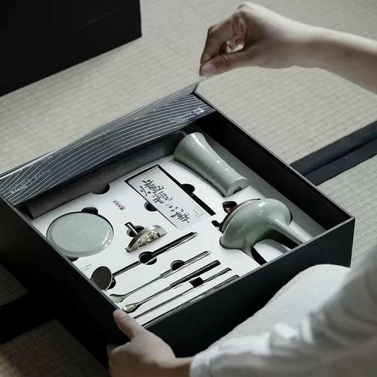 Person opening Incense Bath Ceremony Set showing celadon incense burner and organized tools in foam inlay inside black gift box