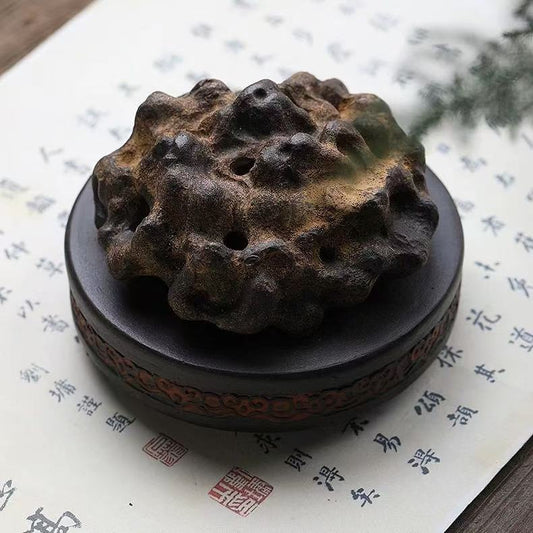 Rock-form handmade purple clay incense burner in Sandalwood Brown color placed on calligraphy paper