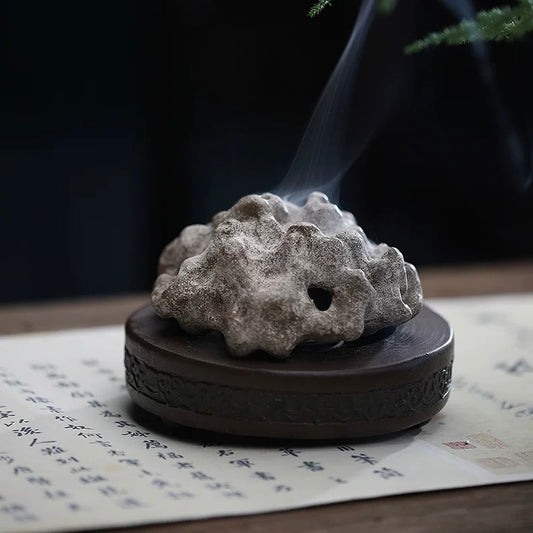 Rock-form handmade purple clay incense burner in Tear White color, emitting smoke on tabletop