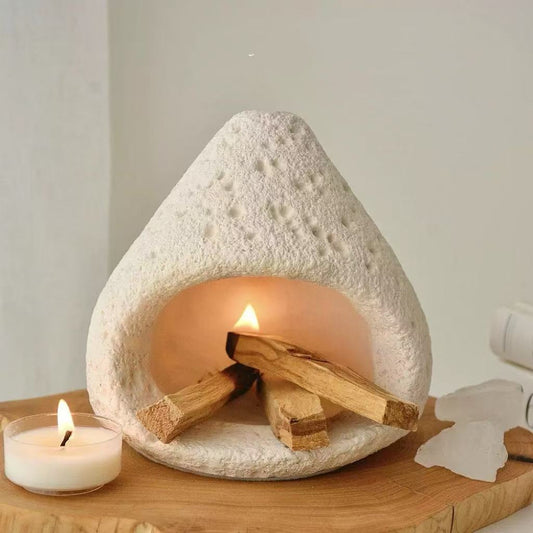 Natural white stone incense burner with wooden tray, burning wood incense pieces inside, accompanied by a small tealight candle on the side