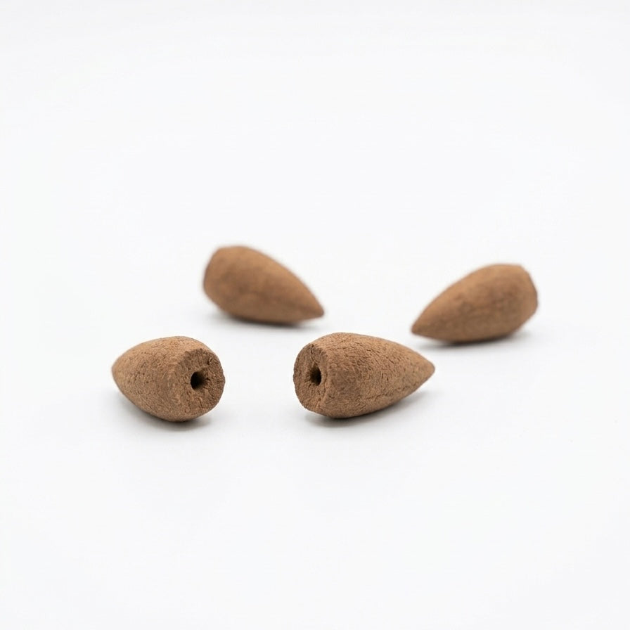Four brown Hainan agarwood backflow incense cones displayed on a white background, showing their tapered shape and hollow center openings for backflow smoke.