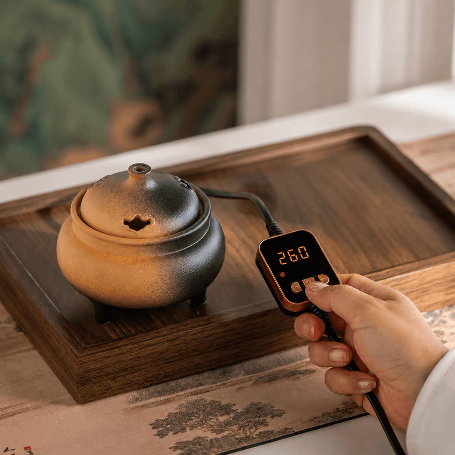 Hand adjusting the temperature controller of a ceramic electric incense burner to 260°C for precise flameless incense heating.