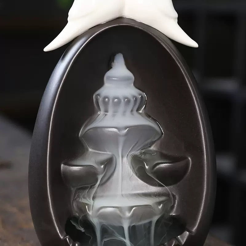 Close-up view of the Backflow Incense Burner Ceramic Waterfall with Doves, showing thick white incense smoke cascading down the layered ceramic fountain channels beneath the white dove topper