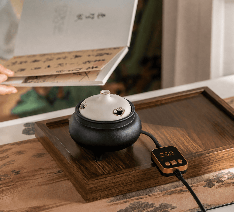 Black and white ceramic electric incense burner with temperature controller on a wooden tray, shown with gift packaging for flameless incense heating.
