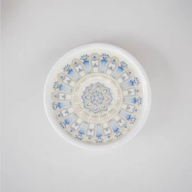 Bottom view of a round blue and white ceramic lotus incense holder showing the decorative floral pattern on the base