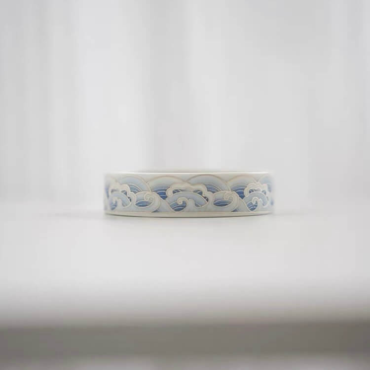 Side view of a blue and white ceramic lotus incense holder showing the decorative wave pattern around the round base