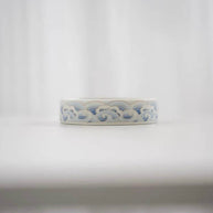 Side view of a blue and white ceramic lotus incense holder showing the decorative wave pattern around the round base