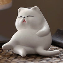 White ceramic cat incense holder in a relaxed sitting pose on a woven surface, front angle, no incense stick inserted.