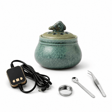 Ceramic electric incense burner set with temperature controller, metal dish, spoon, and tweezers on a clean white background.