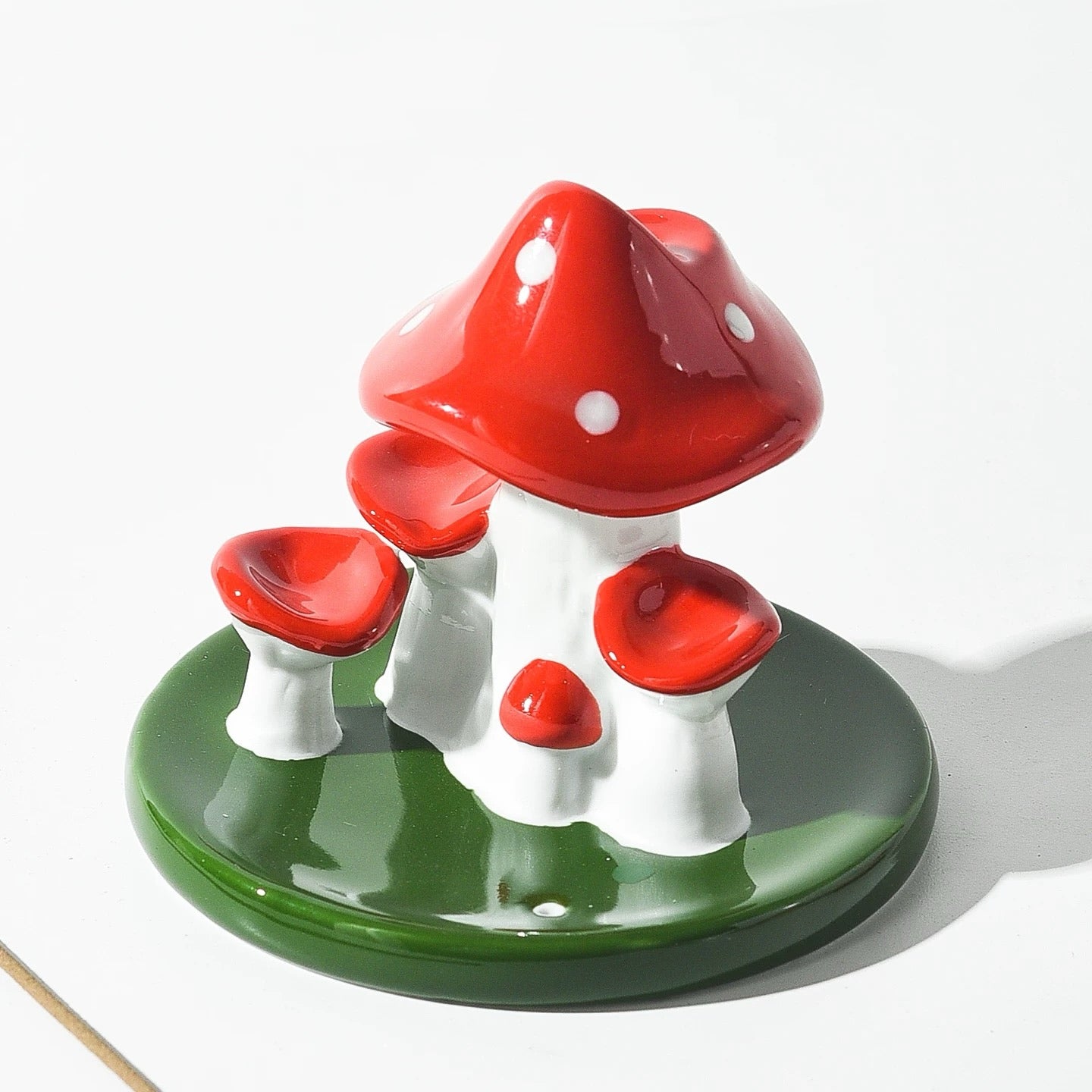 Close up view of red and white ceramic mushroom incense burner with green leaf base showing glossy porcelain finish