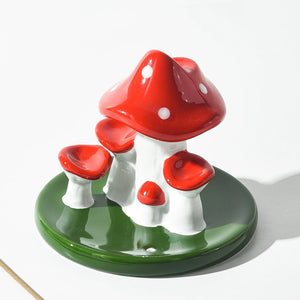 Close up view of red and white ceramic mushroom incense burner with green leaf base showing glossy porcelain finish