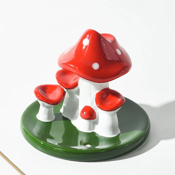 Close up view of red and white ceramic mushroom incense burner with green leaf base showing glossy porcelain finish