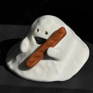 Hand-painted ceramic ghost incense holder for cone incense in glossy white, dramatic lighting on a dark stone shelf.