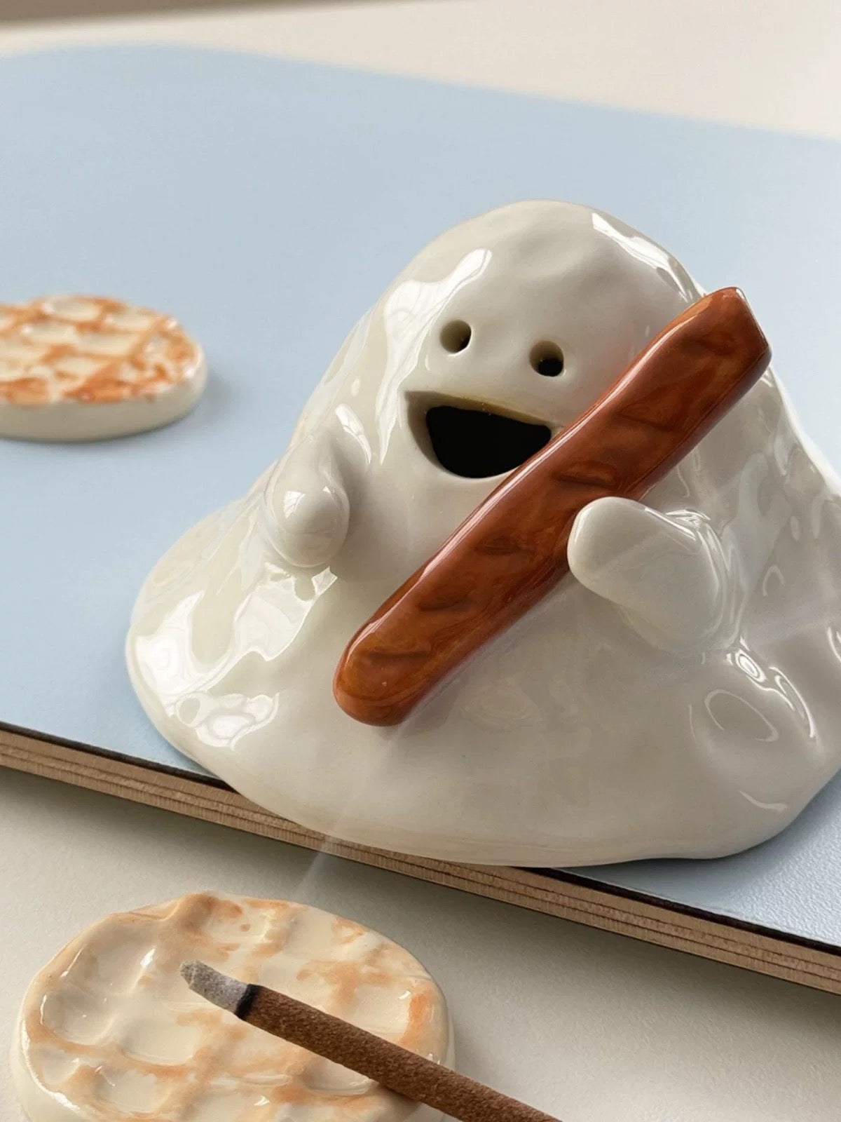 Hand-painted ceramic ghost incense holder for cone incense, glossy white with matching bases in a lifestyle scene.