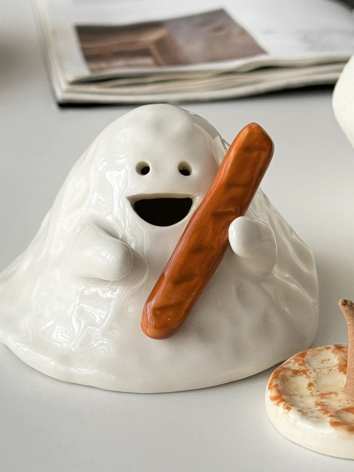 Hand-painted ceramic ghost incense holder for cone incense, glossy white with matching base on a tabletop, lifestyle scene.