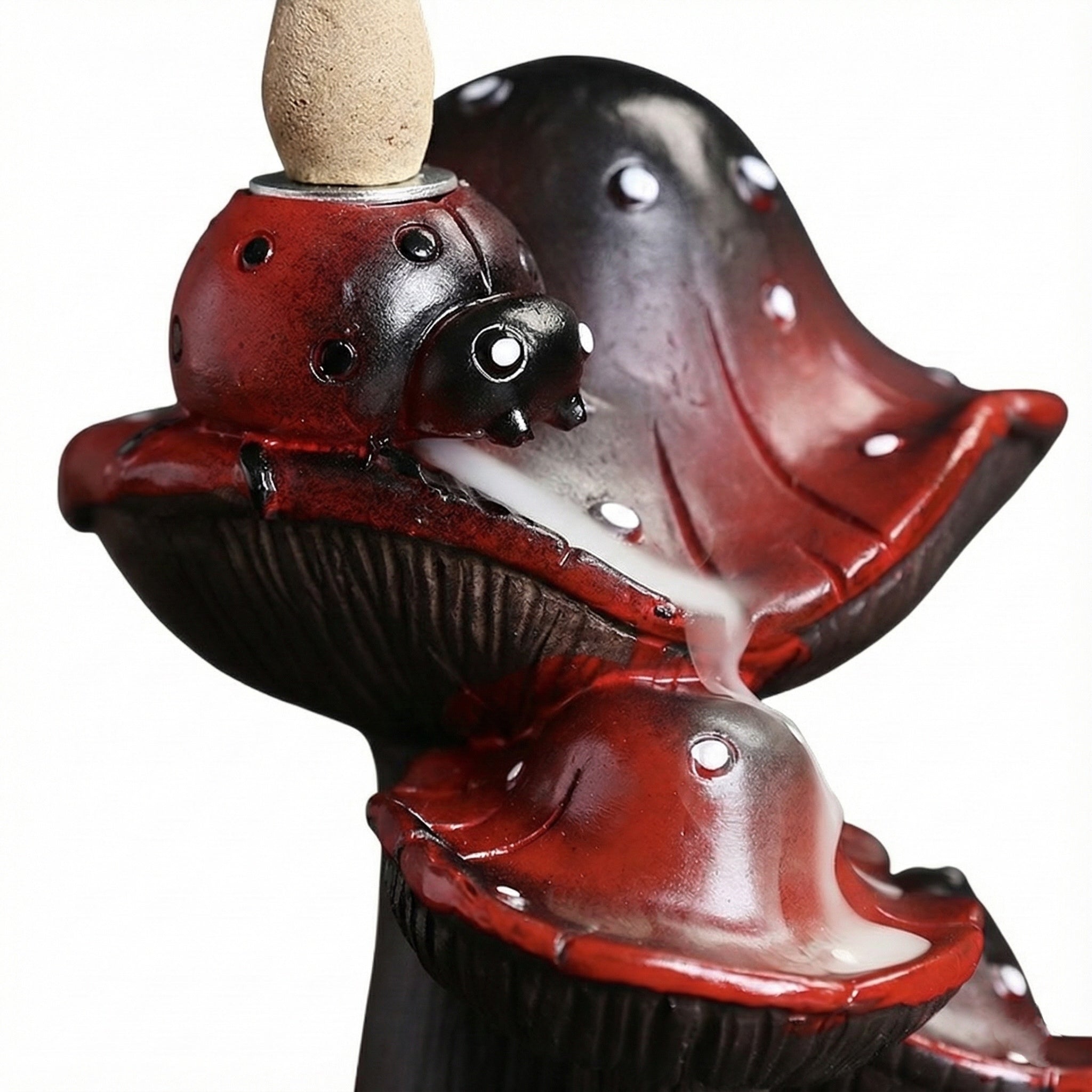 Close-up of a creative resin mushroom backflow incense burner featuring red and black mushroom caps with white spots, designed to let incense smoke cascade downward like a misty waterfall.