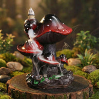 Creative resin mushroom backflow incense burner featuring a cluster of red and black mushrooms with smoke cascading downwards like a misty waterfall on a wooden base with a mossy background.