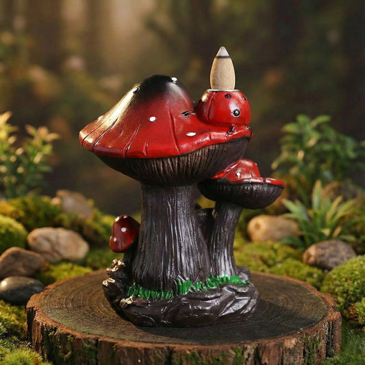 Side view of the creative resin mushroom backflow incense burner showcasing the detailed texture of the dark stems and vibrant red caps with an unlit incense cone placed on top resting on a wood slice.