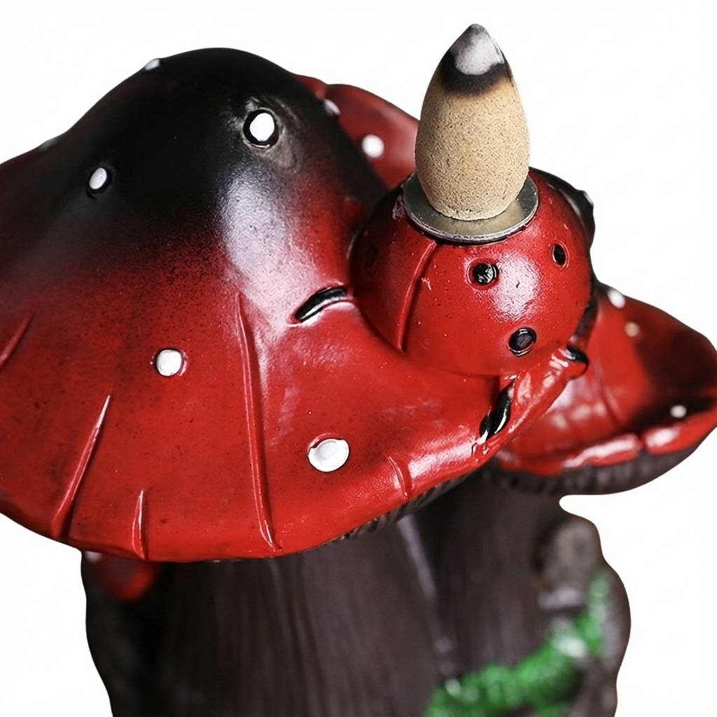 Extreme close up detail of the red mushroom incense burner top showing the glossy texture of the cap and an unlit incense cone sitting on the metal holder.