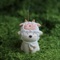 Custom handmade ceramic incense holder featuring a cute bear in a sheep costume with a lit incense stick displayed on green moss
