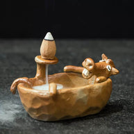 Side view of a cute brown animal bathtub backflow incense burner with a cone releasing smoke into the small tub