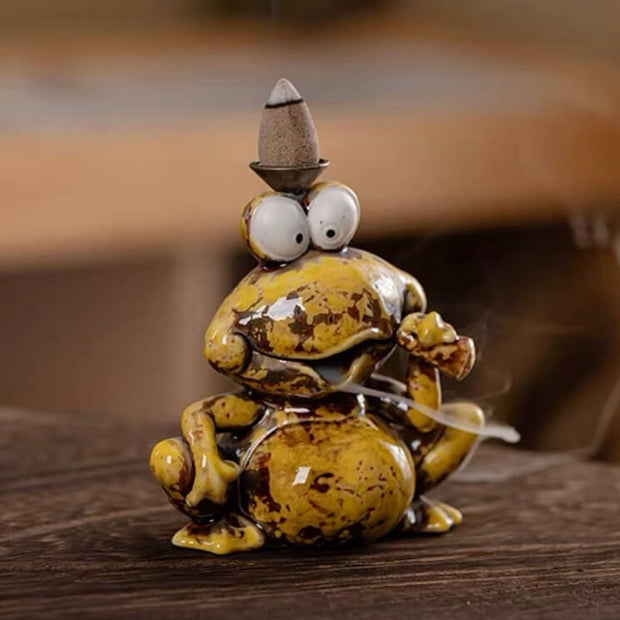 Cute yellow frog playing a violin with a backflow incense cone holder on its head displayed on a wooden surface