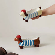 Light blue dachshund incense holder held in hand above a brown striped version on a white backdrop for size reference.