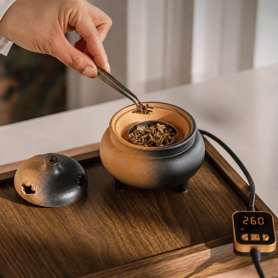 Adding incense chips with tweezers into a ceramic electric incense burner with 260°C temperature control for flameless home fragrance.