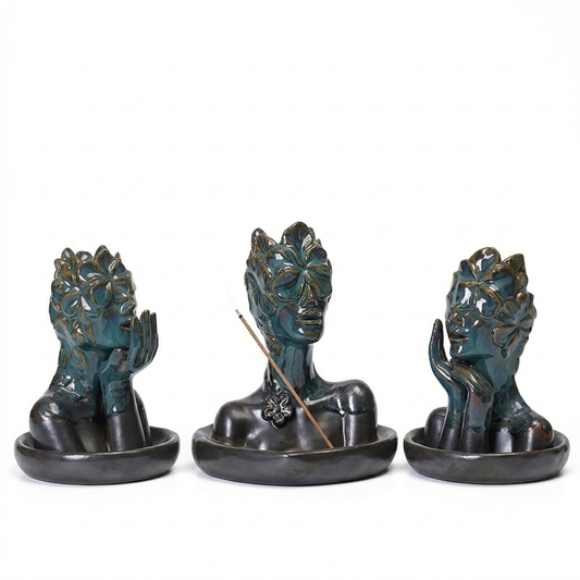 A three-piece set of glossy blue-green ceramic incense burner sculptures featuring abstract floral mask busts in different poses, each displayed on a dark oval base, with the center piece including a stick incense holder.