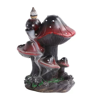 Front view of a creative resin backflow incense burner featuring a whimsical cluster of dark red and black mushrooms with white spots. A lit incense cone rests on top, creating a mesmerizing and soothing smoke waterfall effect that cascades down the mushroom caps to a rocky, moss-accented base. Perfect for unique nature-inspired room decor and relaxing aromatherapy.