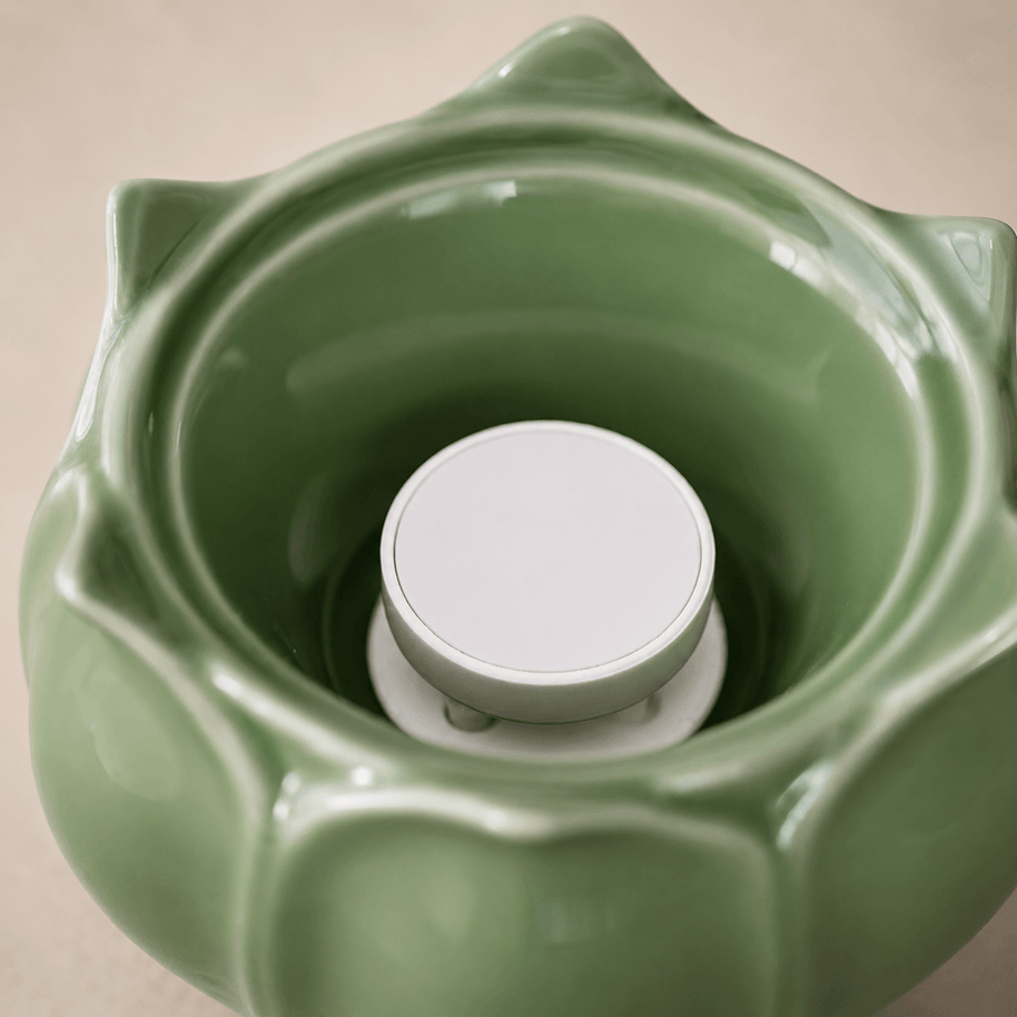 Close up view of the ceramic heating chamber inside a green lotus electric incense burner showing the built in heating plate