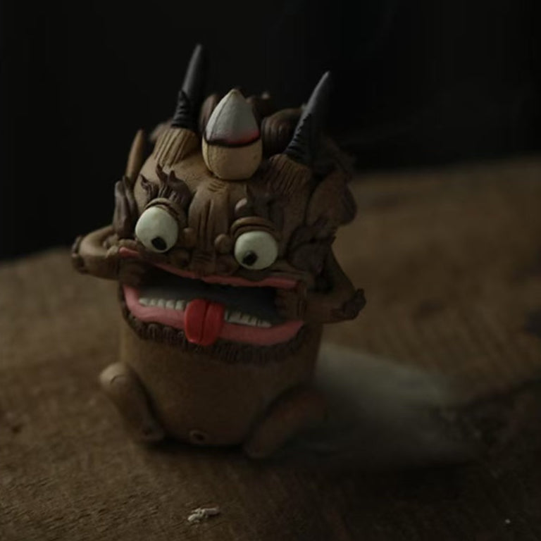 Close‑up of a handcrafted purple clay guardian backflow incense burner, highlighting its textured clay, expressive mouth with red tongue, and cascading mist.