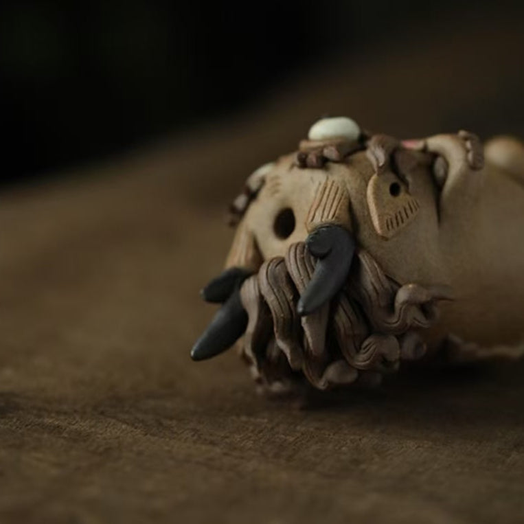 Close‑up of the top section of a handcrafted purple clay guardian backflow incense burner, highlighting its carved horn tips, swirling clay mane, and the incense cone seated on its head.