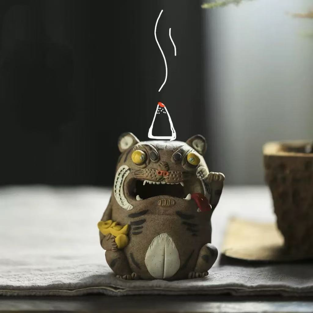 Handcrafted purple clay tiger guardian backflow incense burner displayed in use with a lit cone on top, showing curling smoke above the tiger figure in a warm tabletop setting.