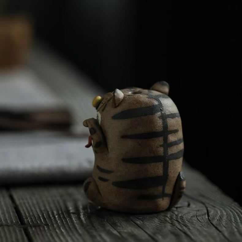 Rear view of the handcrafted purple clay tiger guardian incense burner, showing hand-painted black tiger stripes, rounded purple clay body, and handmade ceramic texture on a rustic wooden tabletop.