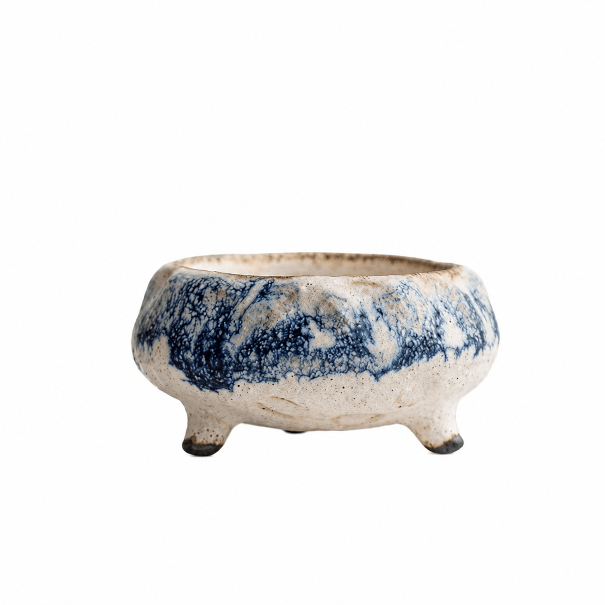 Handmade cream ceramic incense holder with blue marbled glaze and three short feet displayed on a white background