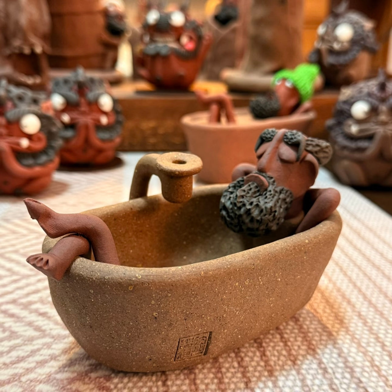 Angled view of the handmade ceramic backflow incense burner featuring The Relaxing Sage reclining in a bathtub in a cozy decorative indoor setting