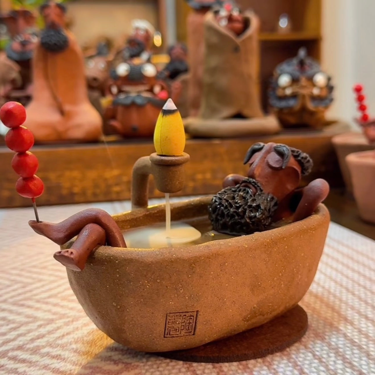 Handmade ceramic backflow incense burner featuring The Relaxing Sage reclining in a bathtub with an incense cone in a warm indoor setting