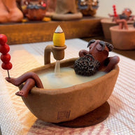 Handmade ceramic backflow incense burner featuring The Relaxing Sage relaxing in a bathtub with an incense cone and flowing smoke in a warm cozy interior setting