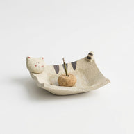 Handmade ceramic incense holder shaped like a curled cat, featuring a cream-colored dish with painted stripes, a small cat face and tail detail, and a central incense insert on a clean white background.
