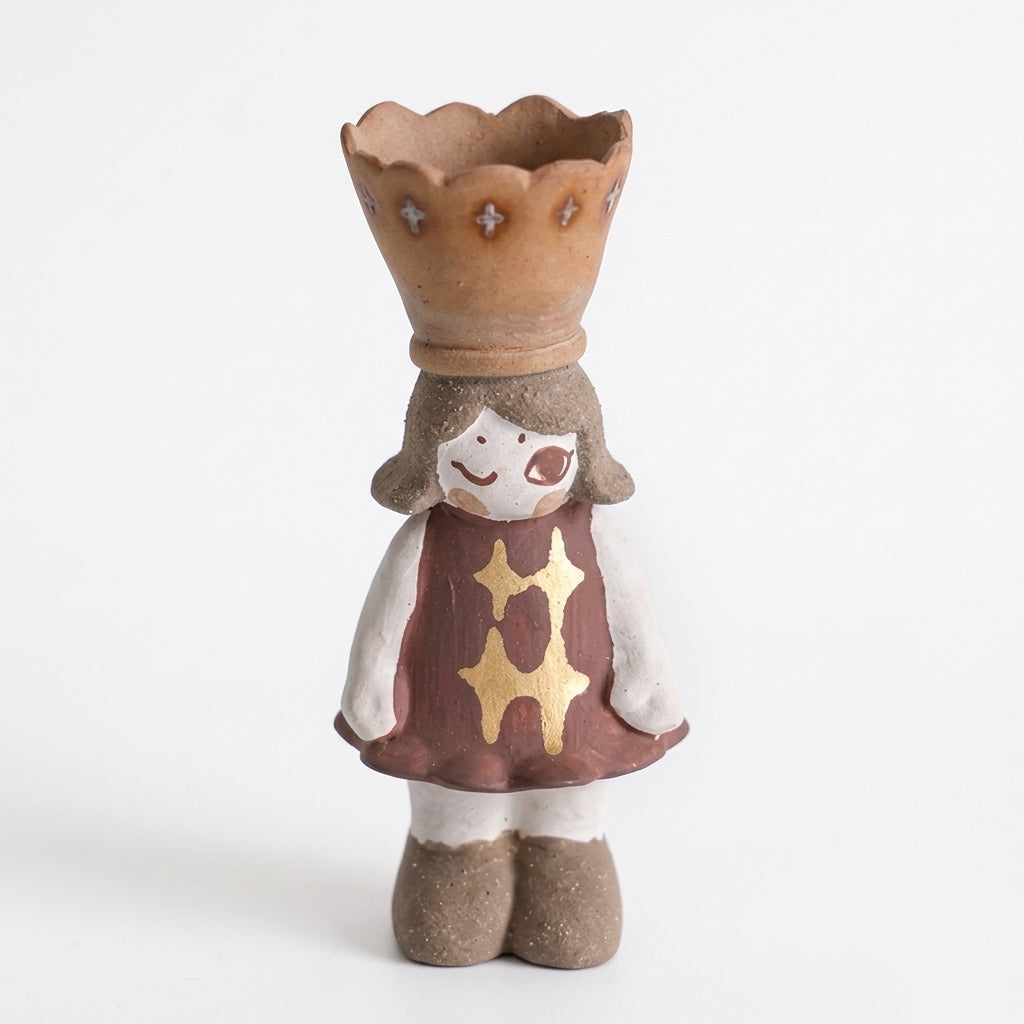 Handmade ceramic crowned girl incense burner figurine with a mauve dress, white sleeves, beige shoes, and a scalloped crown cup, accented with a gold motif on the front, shown against a white background.